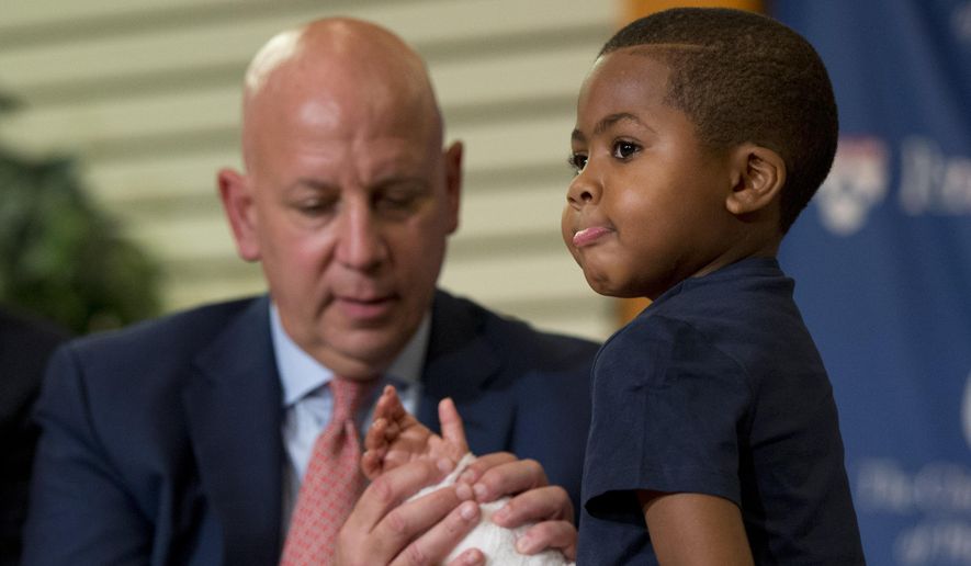 As Dr. L. Scott Levin holds his hand, double-hand transplant recipient 8-year-old Zion Harvey moves his fingers during a news conference Tuesday, July 28, 2015, at The Children’s Hospital of Philadelphia (CHOP) in Philadelphia.  Surgeons said Harvey of Baltimore who lost his limbs to a serious infection,  has become the youngest patient to receive a double-hand transplant. (AP Photo/Matt Rourke)