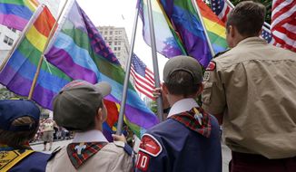 In this Sunday, June 28, 2015 photo, Cub Scouts and Boy Scouts prepare to lead marchers while waving rainbow-colored flags at the 41st annual Pride Parade in Seattle, two days after the U.S. Supreme Court legalized gay marriage nationwide. On Monday, July 27, 2015, the Texas-based Boy Scouts of America ended its blanket ban on gay adult leaders but will allow church-sponsored Scout units to maintain the exclusion for religious reasons. (AP Photo/Elaine Thompson/File)