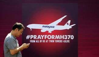 A man walks past a board reading &quot;Pray for MH370&quot; in Kuala Lumpur, Malaysia, on March 15, 2014. (Associated Press)