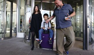 Chinese dissident artist Ai Weiwei, right, his wife Lu Qing, left, and his son Ai Lao arrive at the airport in Munich, Germany,  Thursday, July 30, 2015. Ai Weiwei is on his way to Berlin where part of his family lives. (AP Photo/Matthias Schrader)