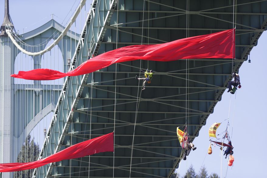 Activists hang off the St. Johns Bridge to protest Shell Oil's drilling in the Arctic, in Portland, Ore., Wednesday, July 29, 2015. The thirteen protesters dangled from the bridge while another 13 remained on the bridge as lookouts. Greenpeace USA executive director Annie Leonard said the activists have enough water and food to last for days, and can hoist themselves to allow other marine traffic to pass. (Kristyna Wentz-Graff/The Oregonian via AP) MAGS OUT, TV OUT, NO LOCAL INTERNET (THE MERCURY, WILLAMETTE WEEK, PAMPLIN MEDIA GROUP OUT)