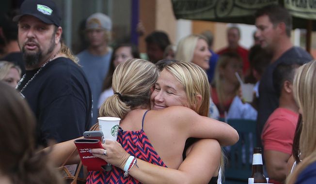 Carly Black, right, mother of Austin Stephanos, gets a hug at Jumby Bay Island Grill, Wednesday, July 29, 2015, in Jupiter, Fla., during a fundraiser to pay for the private search efforts for Nick Cohen and Austin Stephanos, who have been missing since they took their boat out of the Jupiter Inlet, Friday. (Richard Graulich/The Palm Beach Post via AP)