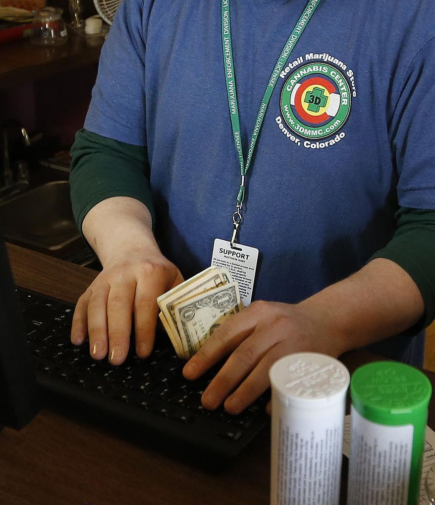 FILE - In this May 8, 2014 file photo, an employee works the register, receiving cash at a retail marijuana store, in Denver. A new credit union serving marijuana businesses has been rejected by federal banking regulators, snuffing another attempt by the federally illegal industry to access financial services. The credit union was granted a state license last year, but it needed permission from the Federal Reserve before opening for business. (AP Photo/Brennan Linsley, file)