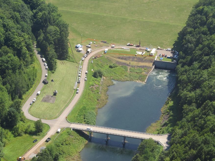 In this Monday, July 27, 2015 aerial photo provided by New York City's Department of Environmental Protection, water flows from a spillway beneath the Cannonsville Dam into the Delaware River in Deposit, N.Y. The DEP is draining about a billion gallons of water a day from the upstate reservoir, 120 miles northwest of the city, as it works urgently to plug a leak near its dam. The reservoir can hold 95 billion gallons and usually accounts for 12 percent of the city’s water. (New York City Department of Environmental Protection via AP)