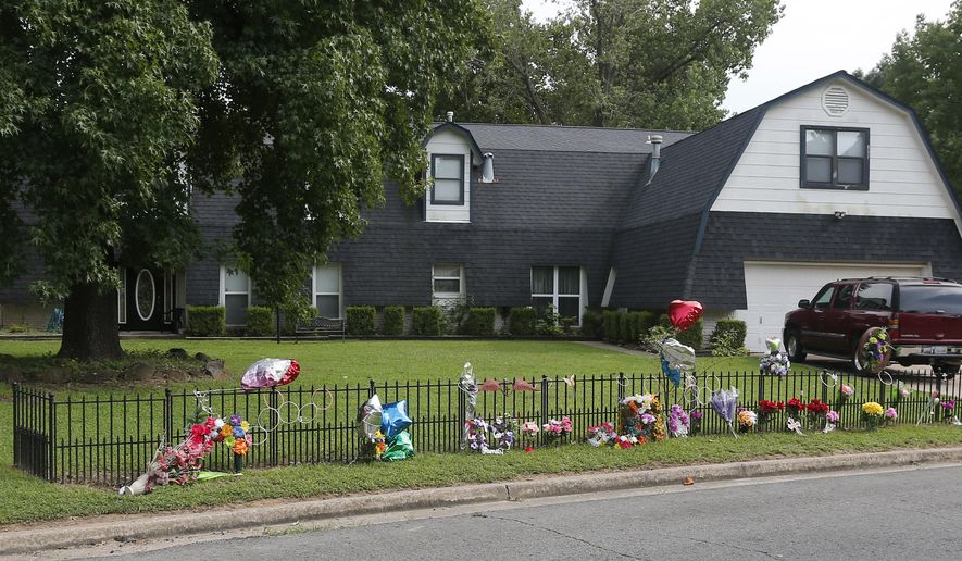 A memorial with flowers and balloons at the fence of the Bever home in Broken Arrow, Okla., is pictured Thursday, July 30, 2015, a week after five family members were found murdered at the home. Neighbors in this quiet Tulsa suburb are still coming to grips with how such brutality could happen here. (AP Photo/Sue Ogrocki)