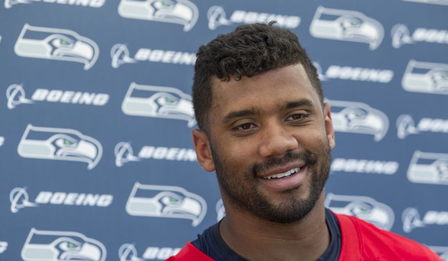 Seattle Seahawks quarterback Russell Wilson smile during a news conference after an NFL football training camp on Friday, July 31, 2015, in Renton, Wash. Wilson signed a four-year $87 million contract. Wilson signed a four-year contract extension with the Seahawks on Friday, keeping him with the franchise that took him in the third round of the 2012 draft and watched him become one of the most successful young quarterbacks in NFL history. (AP Photo/Stephen Brashear)

