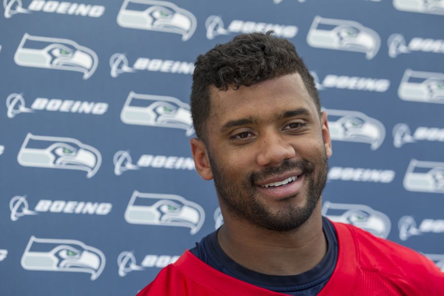 Seattle Seahawks quarterback Russell Wilson smile during a news conference after an NFL football training camp on Friday, July 31, 2015, in Renton, Wash. Wilson signed a four-year $87 million contract. Wilson signed a four-year contract extension with the Seahawks on Friday, keeping him with the franchise that took him in the third round of the 2012 draft and watched him become one of the most successful young quarterbacks in NFL history. (AP Photo/Stephen Brashear)
