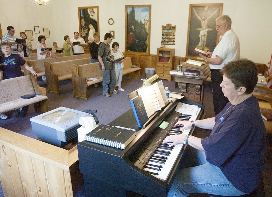 Organist Susie Richards and the Rev. Danny Fleming are shown singing at the front of the Big Isaac United Methodist Church in Big Isaac, W.Va., Sunday, May 20, 2007. Rev. Fleming juggles a full-time job with the U.S. Army in Clarksburg and ministers to two churches some Sundays and three others. He spends 20 hours preparing sermons and logs 100 miles on his truck a week. (AP Photo/Bob Shaw/File)