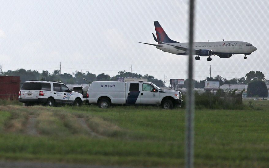 A Delta flight passes over K-9 officers with the Jefferson Parish Sheriff's Office after a drunk driver crashed through two fences at Louis Armstrong New Orleans International Airport and abandoned his blue Dodge Challenger on a runway on Wednesday, Aug. 5, 2015. Kaleb Clement, 23, of Paulina, Louisiana was arrested after a short chase. There were no injuries reported. (Michael DeMocker/The Times-Picayune via AP) NO MAGS, NO SALES, NO TV, USA TODAY OUT, NEW ORLEANS ADVOCATE OUT