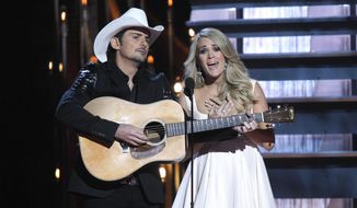 In this Nov. 5, 2014, file photo, Brad Paisley, left, and Carrie Underwood perform as they host the 48th annual CMA Awards in Nashville, Tenn. Underwood and Paisley will return to host the Country Music Association Awards on ABC this fall for an eighth straight year. The 49th annual awards show will air live from Bridgestone Arena in Nashville, Tenn., on Nov. 4. (Photo by Wade Payne/Invision/AP, File)