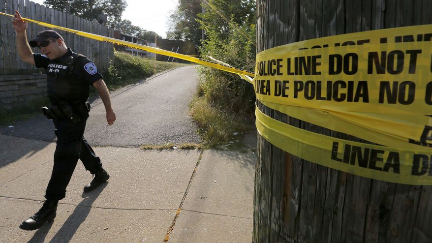 A Richmond police officer walks out of an alley at the scene of a shooting involving a police officer, in the Fan District of Richmond, Va., Wednesday, Aug. 5, 2015. An armed suspect fired first at two police officers and they were justified in returning gunfire and killing the suspect, Richmond Police Chief Alfred Durham said Thursday. (Bob Brown/Richmond Times-Dispatch via AP)