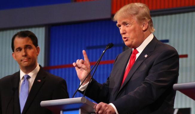 Republican presidential candidate Donald Trump speaks as Wisconsin Gov. Scott Walker listens during the first Republican presidential debate at the Quicken Loans Arena Thursday, Aug. 6, 2015, in Cleveland. (AP Photo/Andrew Harnik)