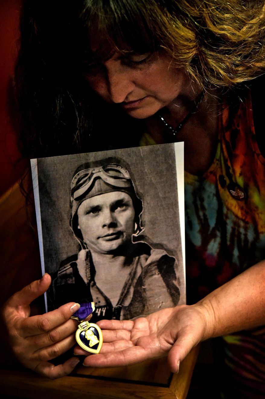 In this Thursday, Aug. 6, 2015, photo, Tami Heart poses for a photo as she holds a picture of World War II B-24 bomber crew member Wiljo Matalamaki and his Purple Heart, in White Bear Lake, Minn. Heart inherited the stranger's Purple Heart from her mother, who found it in a dump near a cabin the family purchased in northern Minnesota. She learned that the medal was awarded Matalamakie, who grew up in the cabin and was killed at age 22 when his plane was shot down during a bombing raid on Germany in June 1944. Heart will be returning the medal to Matalamaki's relatives Sunday, Aug. 9, in a ceremony at the Fort Snelling Memorial Chapel, near Historic Fort Snelling. (Jean Pieri/Pioneer Press via AP)