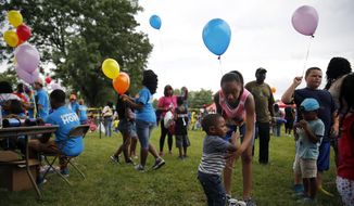 In this July 25, 2015, photo, children hold balloons at a community gathering in Ferguson, Mo. Dubbed a “Day of Hope” more than 40 area churches along with help from Convoy of Hope organized the event to bring people in the community together for a &quot;stress free&quot; day. (AP Photo/Jeff Roberson)