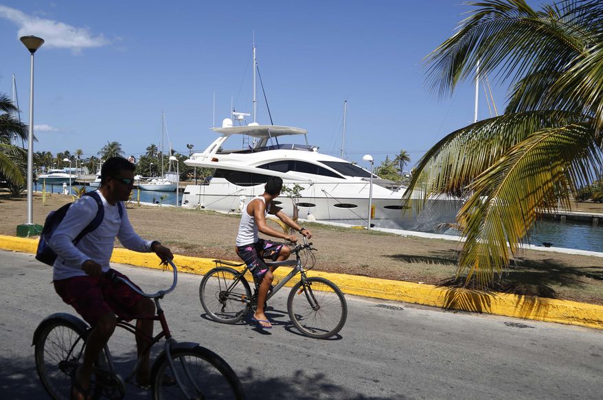 A couple of youths cycle past the U.S yacht Still Waters, moored at the Hemingway Marina in Havana, Cuba, Thursday, Aug. 6, 2015. “The elimination of restrictions on nautical tourism by the U.S. government appears as if it will happen over the short term,” said Jose Luis Perello, a tourism professor at the University of Havana. “That won’t just open the doors to U.S. yachters and other tourists, but (also) to many from other countries and yacht clubs.” (AP Photo/Desmond Boylan)