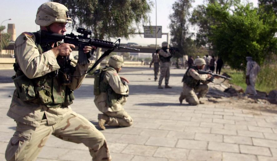 In this Oct. 4, 2003, file photo, American soldiers aim toward a stone-throwing mob of ex-Iraqi soldiers near a former military airport in central Baghdad, Iraq. (AP Photo/Khalid Mohammed, File)