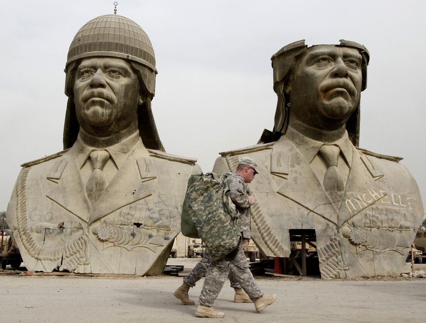 FILE - In this March 20, 2009, file photo, U.S. Army soldiers stroll past two bronze busts of former Iraqi President Saddam Hussein in the Green Zone in Baghdad, Iraq. Under its leader, Iraqi jihadi Abu Bakr al-Baghdadi, the Islamic State group's top command is dominated by former officers from Saddam's military and intelligence agencies, according to senior Iraqi officers and top intelligence officials. (AP Photo/Hadi Mizban, File)