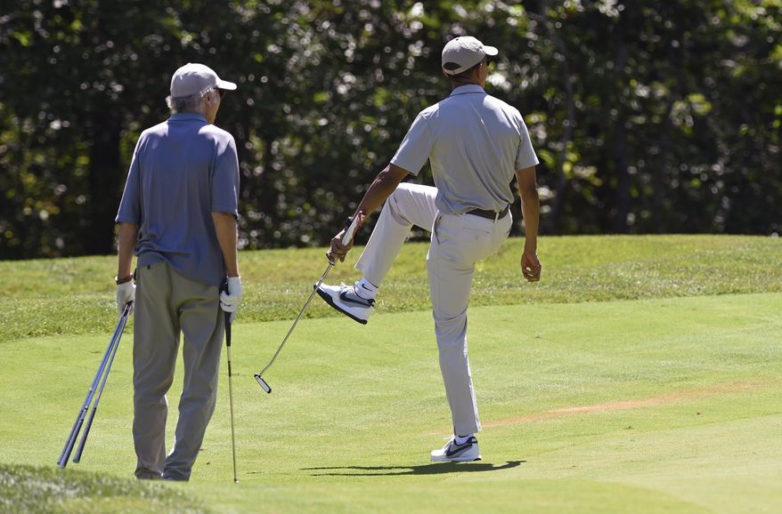 President Barack Obama, right, watches his ball as he plays golf on the first hole with Larry David, left, at Farm Neck Golf Course in Oak Bluffs, Mass., on Martha's Vineyard, Saturday, Aug. 8, 2015. The president is returning to his summer vacation spot of choice, the Massachusetts island of Martha's Vineyard, for more than two weeks of hoped-for rest coupled with extended pursuit of his favorite leisure sport: golf. (AP Photo/Susan Walsh)