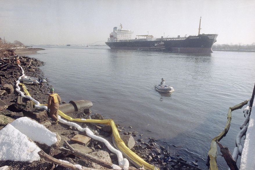 FILE - In this Tuesday, Jan. 9, 1990 file photo, an oil spill cleanup work crew stretches a white absorbent boom line along the shoreline of the Arthur Kill waterway in Elizabeth, N.J. Clean up efforts continue to rid the water of up to 500,000 gallons of No. 2 heating oil believed to have escaped from an underwater Exxon pipeline. New Jersey's 11-year suit against ExxonMobil could result in $50 million in legal fees if a Superior Court judge approves the $225 million proposed settlement. (AP Photo/Mike Derer,file)