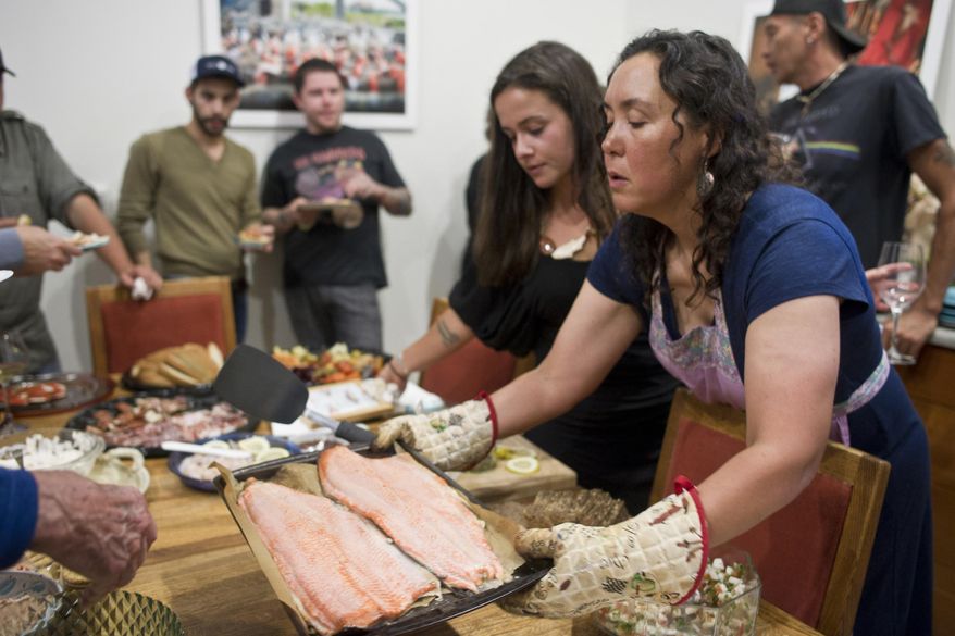 ** ADVANCE FOR SUNDAY AUG. 9, 2015 AND THEREAFTER ** In this photo taken July 29, 2015, Melanie Brown puts out baked salmon with other seafoods during a dinner at her home hosted by Salmon Beyond Borders and The Rookery Café for visiting celebrity chefs in Juneau, Alaska. Salmon Beyond Borders, an organization that defends transboundary salmon rivers from mining effects, joined forces with the Rookery Café last week to welcome celebrity chefs from across the nation. The goal for this two-night experience was to put local salmon in acclaimed hands, showcasing bounty from Alaska waters, while sharing stories of how such bounty can be lost forever when mining disasters strike. (Michael Penn/Juneau Empire via AP)