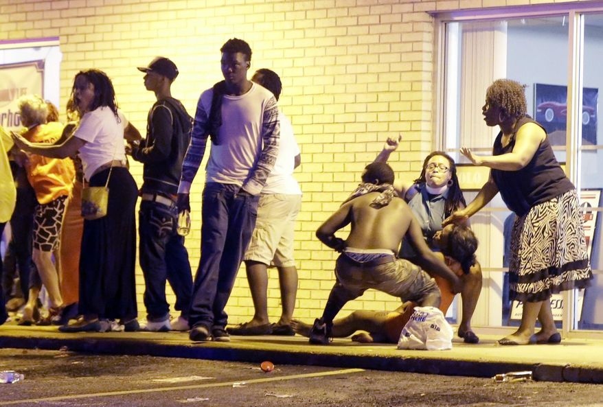 People come to the aid of a distraught woman after gunshots were fired near a protest in Ferguson, Mo., Sunday, Aug. 9, 2015. The one-year anniversary of Michael Brown's death in Ferguson began with a march in his honor and ended with a protest that was interrupted by gunfire. (AP Photo/Jeff Roberson)