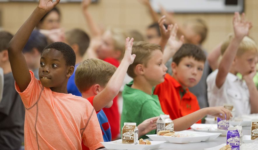 In this Thursday, Aug. 6, 2015 photo, student James Barragan, left, and other students raise their hands during lunch in the cafeteria at Hendron-Lone Oak Elementary in Paducah, Ky. Thursday was the first day of classes for all McCracken County Public Schools.(Ellen O'Nan/The Sun via AP)