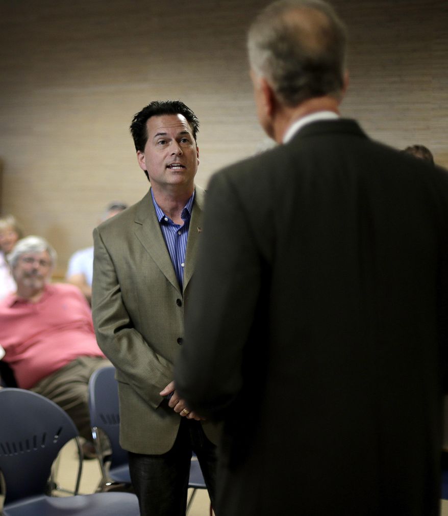 Former tea party-backed candidate Dr. Milton Wolf, left, questions Kansas Sen. Jerry Moran at a town hall meeting Monday, Aug. 10, 2015, in Wamego, Kan. Wolf wanted to know about Moran's knowledge of the state medical board's past investigation of Wolf's license as Wolf was running for office against Kan. Sen. Pat Roberts in 2014. (AP Photo/Charlie Riedel)