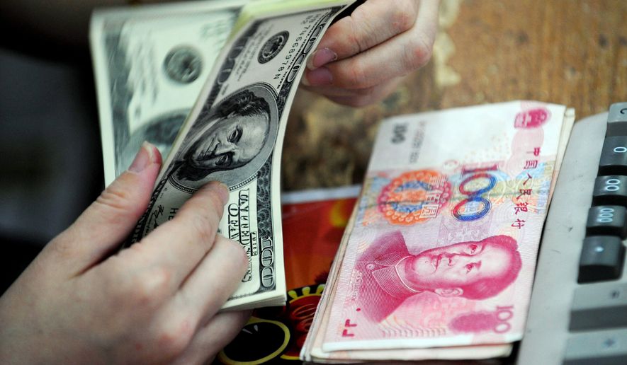 A Chinese clerk counts U.S. dollars in exchange for the Chinese renminbi at a bank in Hefei in central China&#x27;s Anhui province. (Associated Press)