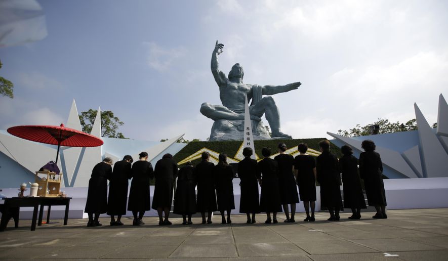 FILE - In this Sunday, Aug. 9, 2015 file photo, visitor offer prayers in front of the Peace Statue at the 70th anniversary of the atomic bombing in Nagasaki, southern Japan. Walt Disney Japan apologized Monday, Aug. 10 after a tweet sent from its corporate Twitter account wished readers “congratulations on a not special day” on the 70th anniversary of the U.S. atomic bombing of Nagasaki. (AP Photo/Eugene Hoshiko, File)