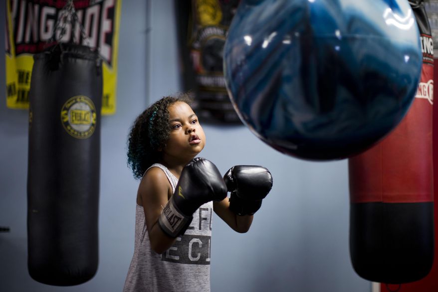 FILE - In this July 22, 2015, file photo, Kennedy Cunningham, 9, the daughter of boxer Steve Cunningham, punches a bag as her father holds a media workout in Philadelphia. It's been a few months now, time that in the Cunningham household is best measured by the decreasing number of visits Kennedy Cunningham makes to the doctor. When her father, Steve Cunningham, returns to the ring this week his mind will be eased knowing his daughter is doing well after receiving a new heart. (AP Photo/Matt Rourke, File)