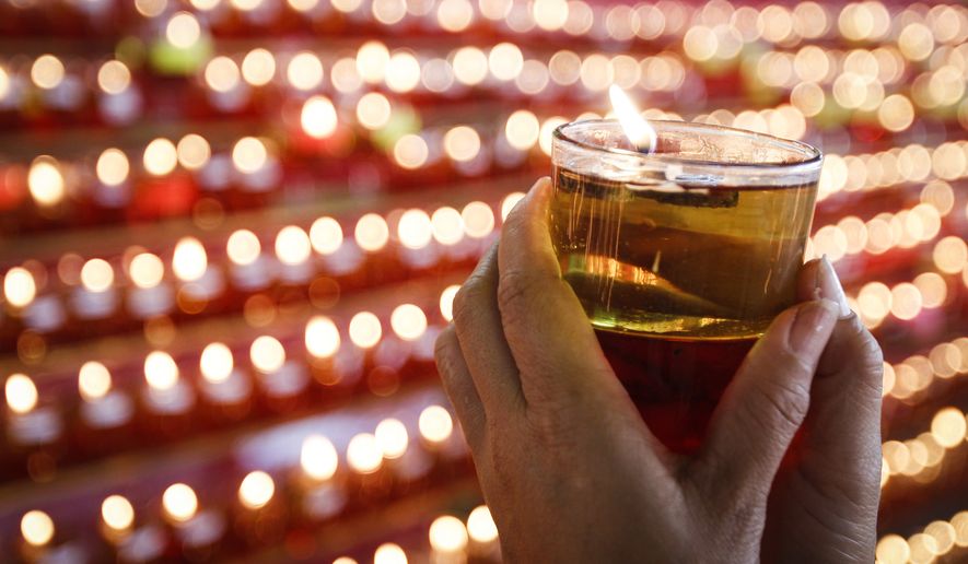 A Buddhist devotee holds an oil lamp as she offers prayers. (AP Photo/Joshua Paul)