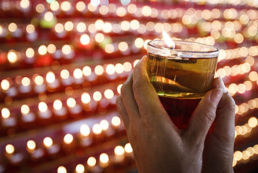 A Buddhist devotee holds an oil lamp as she offers prayers. (AP Photo/Joshua Paul)
