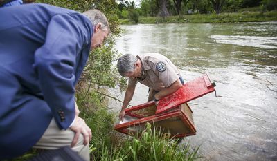 Colorado Governor John Hickenlooper, left, looks at a fish trap on the banks of the Animas River  that is being held by Colorado Parks and Wildlife&#x27;s Aquatic Biologist Jim White in the waters of the river contaminated last week by a massive mine blowout above Silverton, Colo. The Governor toured the area before giving an address to area residents regarding the status ofAnimas River Tuesday, Aug. 11, 2015.  (Shaun Stanley/The Durango Herald via AP)