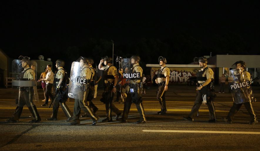Police walk around protesters as people gather along West Florissant Avenue in Ferguson, Mo., Tuesday, Aug. 11, 2015. The St. Louis suburb has seen demonstrations for days marking the anniversary of the death of 18-year-old Michael Brown, whose shooting death by a Ferguson police officer sparked a national &amp;quot;Black Lives Matter&amp;quot; movement. Tuesday was the fifth consecutive night a crowd gathered on West Florissant, the thoroughfare that was the site of massive protests and rioting after Brown was killed. (AP Photo/Jeff Roberson)
