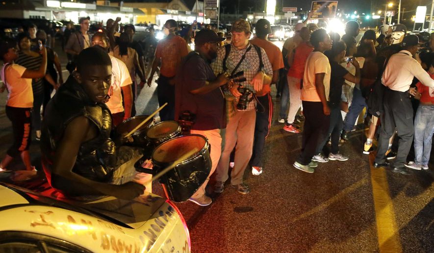 Protesters gather along West Florissant Avenue during a demonstration in Ferguson, Mo., Tuesday, Aug. 11, 2015. The St. Louis suburb has seen demonstrations for days marking the anniversary of the death of 18-year-old Michael Brown, whose shooting death by a Ferguson police officer sparked a national "Black Lives Matter" movement. Tuesday was the fifth consecutive night a crowd gathered on West Florissant, the thoroughfare that was the site of massive protests and rioting after Brown was killed. (AP Photo/Jeff Roberson)
