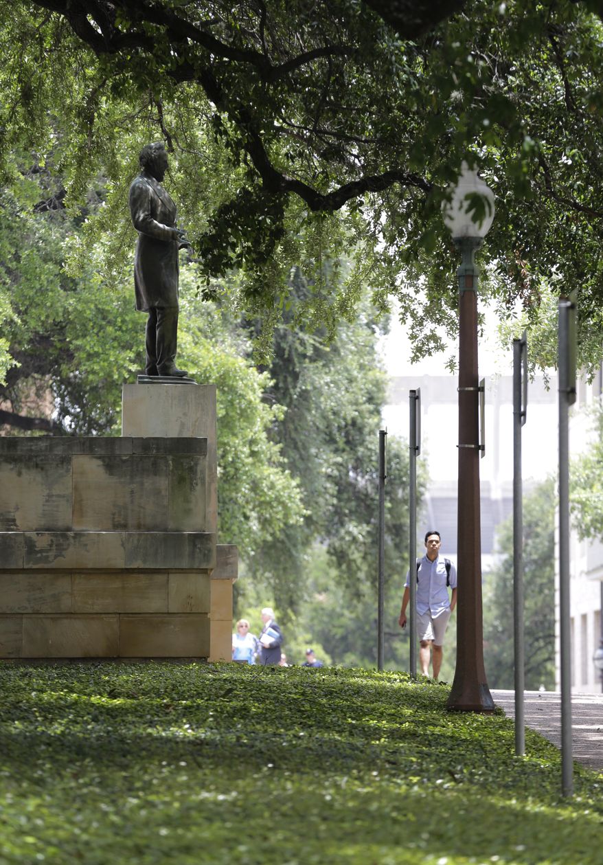 FILE - In this July 7, 2015 file photo, a young man walks near a statue of Jefferson Davis on the University of Texas campus in Austin, Texas. The president of the University of Texas has ordered removing the statue of Davis from the center of campus, but statues of other Confederate figures will stay. The Davis statue has been targeted by vandals and had come under increasing criticism. (AP Photo/Eric Gay, File)