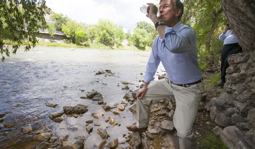 In this Tuesday, Aug. 11, 2015 photo, Colorado Gov. John Hickenlooper drinks water straight from the Animas River  in Durango, Colo., to get an update about the blowout from Gold King Mine. The water was treated with an iodine tablet before he drank it, to kill any giardia. (Shaun Stanley/The Durango Herald via AP) MANDATORY CREDIT