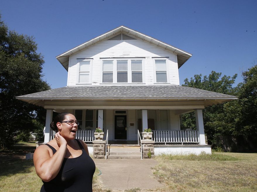 ADVANCE FOR SUNDAY AUG. 16 - In this Tuesday, Aug. 4, 2014 photo, homeowner April McDermott looks down the street while standing in front of her two-story 1902 Victorian Folk home in Marlin, Texas. The McDermott's have launched an essay contest to sell their 4,500 square- foot home with the writer of the winning entry paying $1 to purchase the property. The only catch is a potential home buyers must submit a nonrefundable $100 fee with their essay in order to be considered for the contest. (Rod Aydelotte/Waco Tribune Herald, via AP) MANDATORY CREDIT