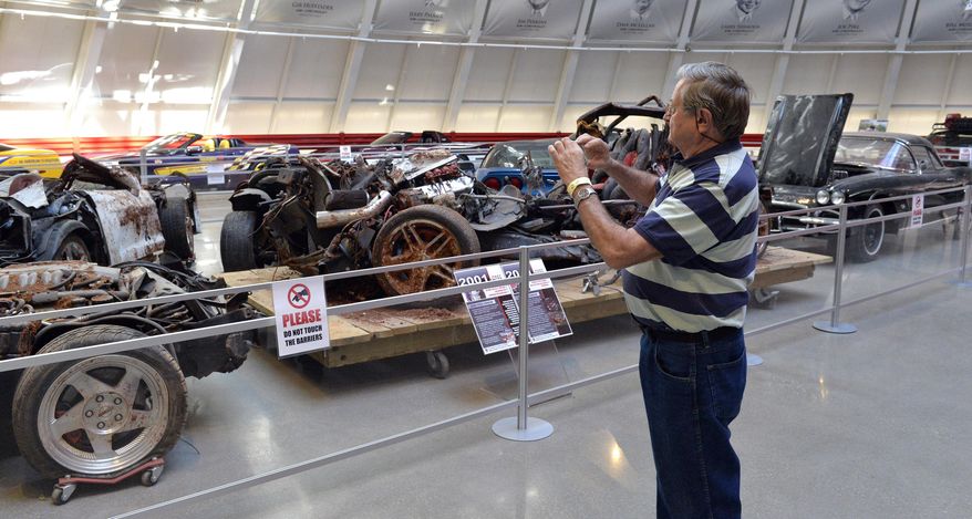 In this Wednesday, Aug. 12, 2015, photo, Terry Jorgensen of Deland, Fla., takes a photo of the cars that were swallowed by the sinkhole at the National Corvette Museum in Bowling Green, Ky. The hole has been fixed but not forgotten at the museum. Yellow tape now marks the boundaries of the cavity that became a sensation and put the museum on the map. (AP Photo/Timothy D. Easley)