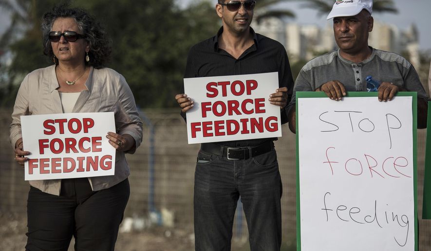 In this photo made on Tuesday, August 11, 2015, Israeli Arab supporters of Mohammed Allan, a Palestinian prisoner on a hunger strike, hold signs during a support rally outside Barzilai hospital, in the costal city of Ashkelon Israel. Israel passed a law to force feed hunger strikers by a slim margin in July and elicited harsh criticism. Critics call force-feeding an unethical violation of patient autonomy and akin to torture. The Israeli Medical Association, which has urged physicians not to cooperate, is challenging the law in the Supreme Court. (AP Photo/Tsafrir Abayov)