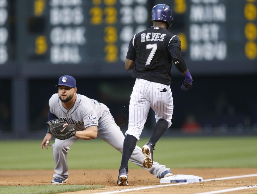 San Diego Padres first baseman Yonder Alonso, left, fields the throw to put out Colorado Rockies' Jose Reyes after his sacrifice bunt to advance base runner Charlie Blackmon from second to third base in the first inning of a baseball game Saturday, Aug. 15, 2015, in Denver. (AP Photo/David Zalubowski)