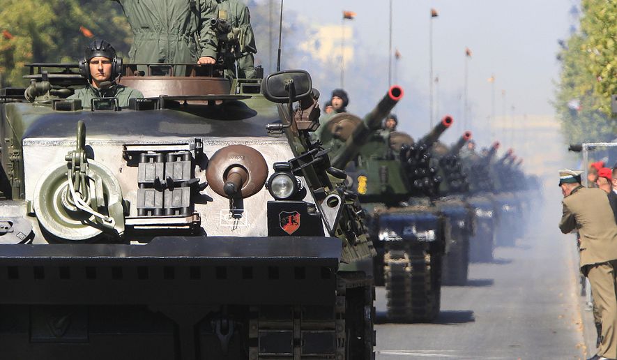 Polish army soldiers salute as tanks roll on one of the city's main streets during a military parade celebrating the Polish Army Day in Warsaw, Poland, Saturday, Aug. 15, 2015. (AP Photo/Czarek Sokolowski)