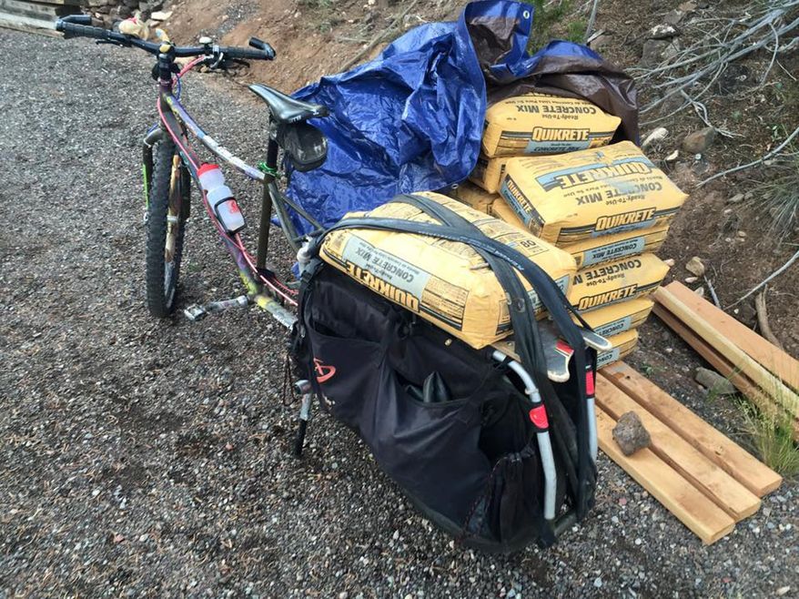 In this Sunday, Aug. 2, 2015 photo, a cargo bicycle loaded with sacks of concrete sits where Steve Novy parked it after riding up a steep grade to the building site of the Oculus, an off-grid clubhouse being built by the Stomparillaz Cycling Collective, near Glenwood Springs, Colo. The off-grid clubhouse with a passive solar design will generate all its own power and heat. Novy rode the cargo bicycle up the grade to keep the project carbon neutral. (Colleen O'Neil/Glenwood Springs Post-Independent via AP)