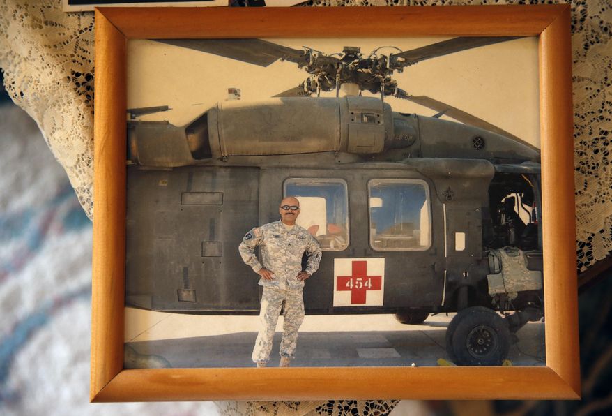 This March 17, 2015 photo shows a photgraph of now-retired U.S. Army Sgt. 1st Class Marshall Powell standing with a U.S. Army MEDEVAC helicopter in Iraq during his last tour to the country, at Powell's brother's house in Crescent, Okla. Powell, who served as a military nurse in Iraq and Afghanistan, was deeply haunted by his experiences, and nearly lost his own internal war with depression before finding meaningful help. (AP Photo/Brennan Linsley)