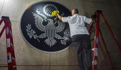 A worker wipes a representation of the The Great Seal of the United States at the newly opened U.S. Embassy in Havana, Cuba. (AP Photo/Ramon Espinosa)