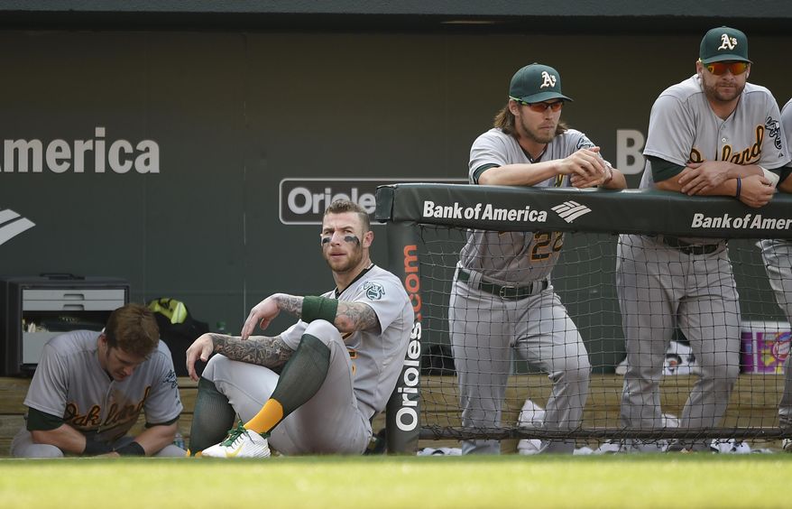 Oakland Athletics' Brett Lawrie, third from right, looks on from the dugout with Josh Reddick, second from right, and Stephen Vogt, right, during the ninth inning of a baseball game against the Baltimore Orioles, Sunday, Aug. 16, 2015, in Baltimore. The Orioles won 18-2. (AP Photo/Nick Wass)