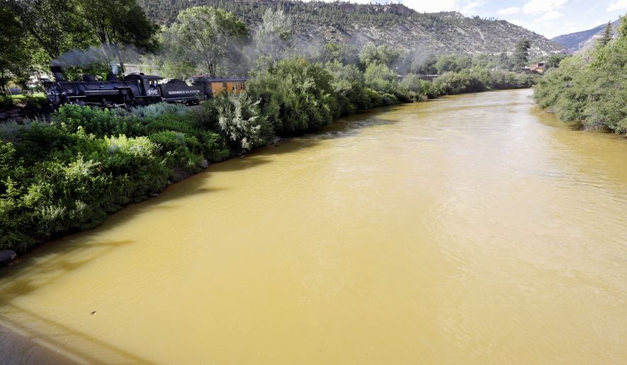 The Animas River flows with toxic waste from the Gold King Mine on Aug. 8, 2015, as seen from the 32nd Street Bridge in Durango, Colo., as the Durango &amp; Silverton Narrow Gauge Railroad train goes by. (Associated Press) **FILE**
