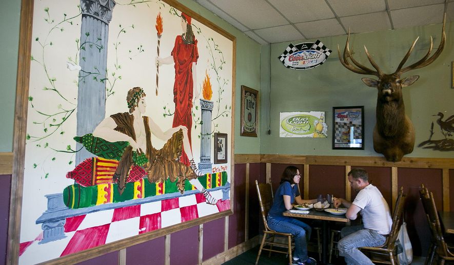 In this photo taken Sunday, Aug. 9, 2015, Glynis Frederiksen and Brian Campbell of Seattle have lunch in the light of a mural painted by local boy makes good, Chris Pratt, at Omega Pizza and Pasta in Granite Falls, Wash. Pratt, best friends with the owner's son, has been known to tie on an apron and help out in the kitchen on one his recent visits. (Kevin Clark/The Herald via AP) MANDATORY CREDIT