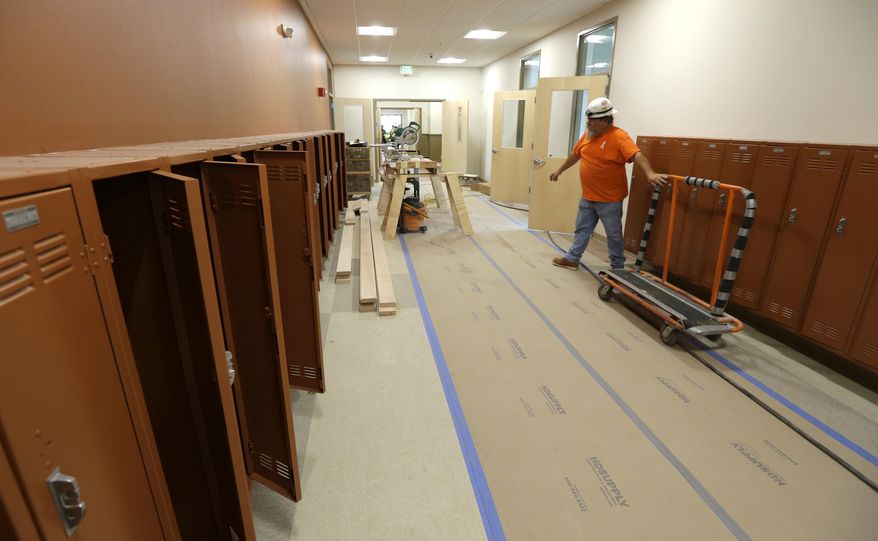In this July 13, 2015 photo, Jerry Kellogg of Master Millwork wheels a lumber cart past open lockers in a hallway of the Destiny Charter Middle School in Tacoma, Wash. The school, which will open in the fall, will start with 200 students in the sixth grade and will be one of nine charter schools operating in the state of Washington during the upcoming school year. (AP Photo/Ted S. Warren)