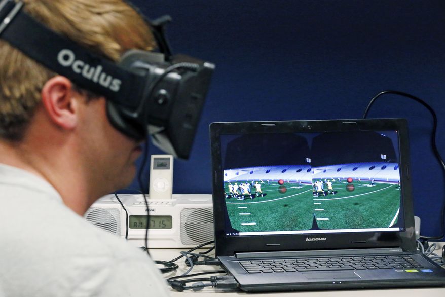 In this July 27, 2015 photo, Mississippi quarterback Ryan Buchanan uses a virtual reality headset to make football play decisions at the Manning Center in Oxford, Miss. Ole Miss is one of a growing number of football programs in the NCAA and NFL dabbling in virtual reality technology to help supplement work on the field. (AP Photo/Rogelio V. Solis)